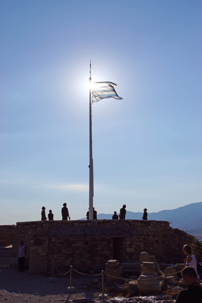 The Greek flag extends under the morning sun.