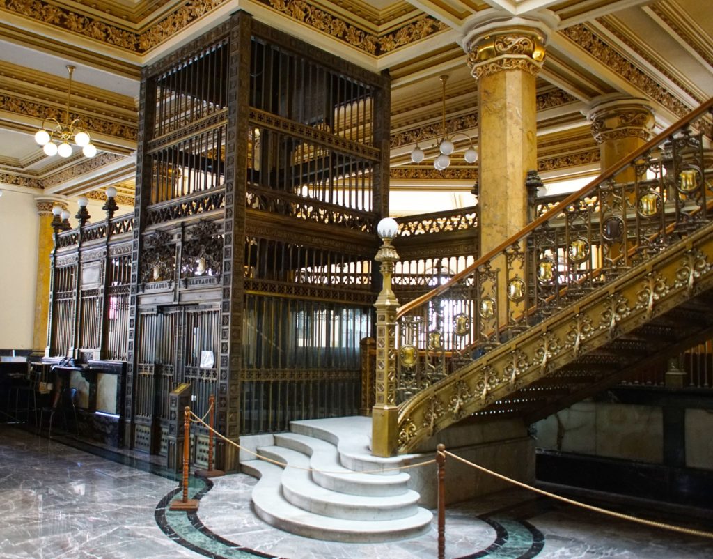 An old-timey elevator still functions, requiring an operator to run the controls.