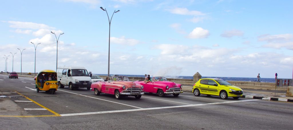 Cubans in colorful cars commuting. 