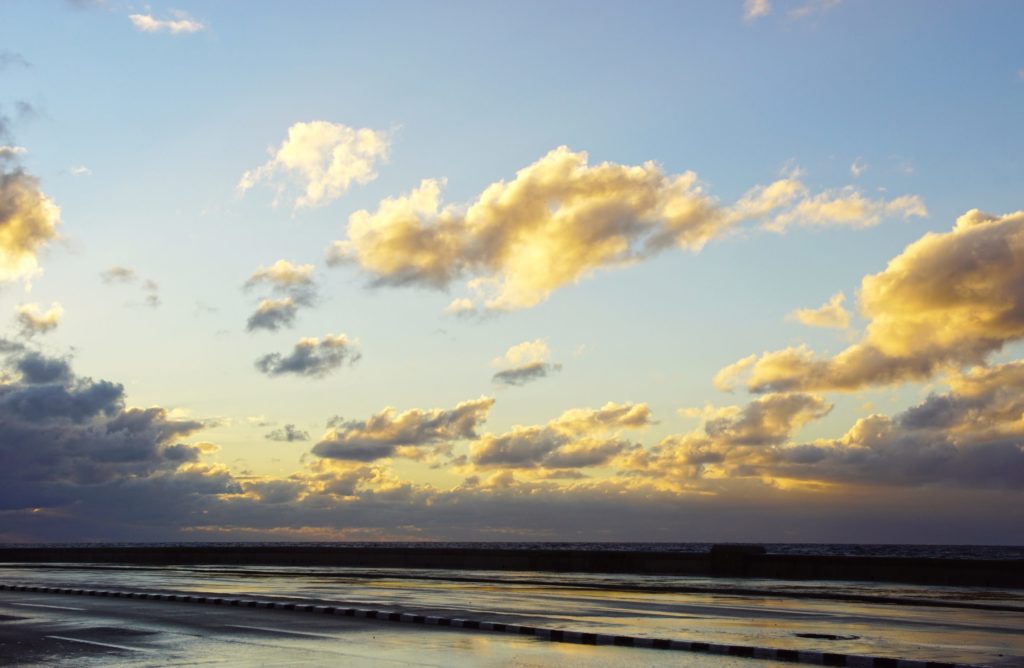 The road glistens from the setting sun reflecting off the sea water.